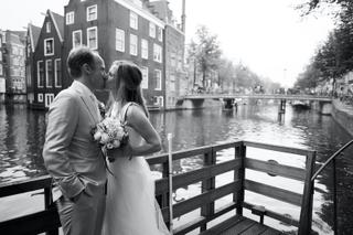 Bruidspaar Mary en Jasper kussen bij kanaal Amsterdam, trouwreportage Wallen - Trouwshoot Stefan Segers