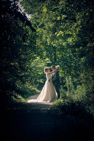 Bruidspaar Angelique en Michiel omhelst elkaar onder groene bladerdak, trouwreportage Fort Beemster Heemskerk - Trouwshoot St