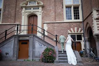 Bruidspaar Liëla en Jeffrey loopt trap op bij historisch bakstenen gebouw - Trouwshoot Stefan Segers
