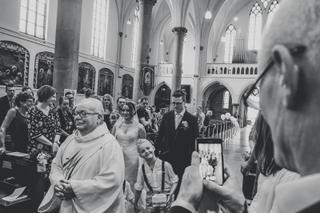 Bruidspaar Joyce en Yuri tijdens trouwceremonie in kerk Breda, gasten en priester tijdens inzegening, klassieke trouwreportag