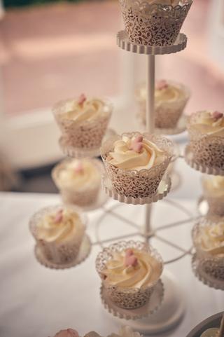 Elegante cupcakes met roomkaas frosting in filigrain wrappers op tiered stand - Trouwshoot Stefan Segers