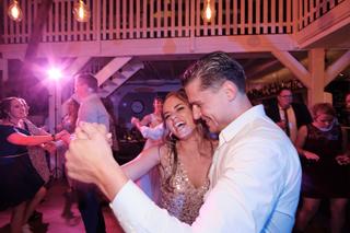 Bruidspaar Barry en Milou dansen vol vreugde onder roze sfeerverlichting op hun feest - Trouwshoot Stefan Segers