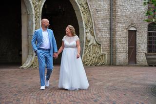 Annemarie en Jan hand in hand voor de prachtige Bosrijkpoort in de Efteling, bruid in ivoor jurk en bruidegom in blauw kostuu