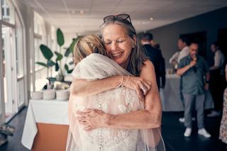 Moeder van de bruid omhelst haar dochter in trouwjurk met emotie en blijdschap op het feest - Trouwshoot Stefan Segers