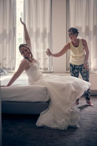 Bruid Ilja en Mike spelen dansend op bed in het Fletcher Hotel Deurne - Trouwshoot Stefan Segers