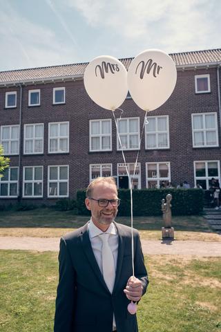 Bruidegom Mike glimlacht met Mrs en Mr ballonnen voor Klein kasteel Deurne - Trouwshoot Stefan Segers
