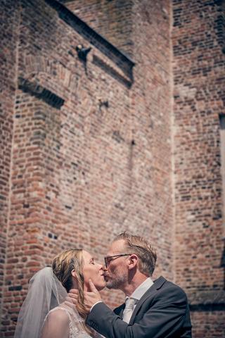 Bruidspaar Mike en Ilja kussen bij historische bakstenen muur Klein kasteel Deurne, trouwreportage Fletcher hotel Deurne - Tr