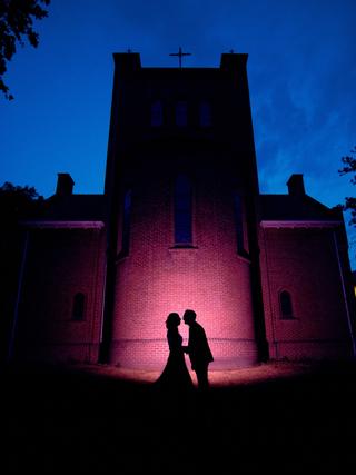 Bruidspaar Ilja en Mike zoenen bij verlicht Klein kasteel Deurne onder stralende blauwe avondlucht - Trouwshoot Stefan Segers