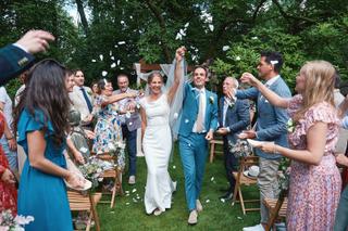 Bruidspaar Niels en Karien verlaat onder confetti hun ceremonie in tuin Villa Dalhof Berg en Dal, trouwreportage met gasten -