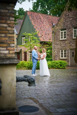 Annemarie en Jan hand in hand op het kinderplein van Efteling, historische bakstenen huizen op achtergrond - Trouwshoot Stefa