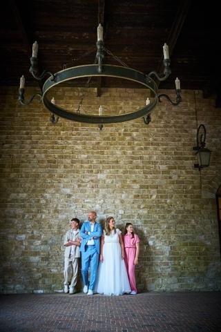 Bruidspaar Annemarie en Jan met hun kinderen tegen bakstenen muur onder vintage kroonluchter in Efteling - Trouwshoot Stefan