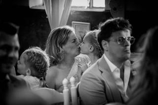Froukje en Mireille kussen innig tijdens hun bruiloft in Blizz Boekel, gasten kijken glimlachend toe - Trouwshoot Stefan Sege