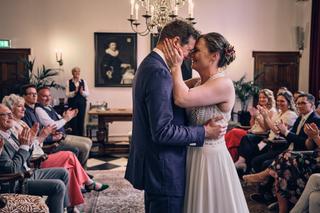 Bruidspaar Simanca en Harm-Jan delen een innig moment tijdens hun trouwceremonie in Delft, omringd door gelukkige gasten - Tr