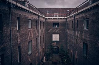 Bruidspaar in de sfeervolle binnenplaats van stadhuis Delft, omgeven door historische bakstenen architectuur - Trouwshoot Ste