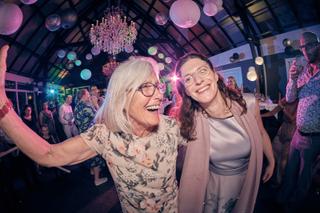 Bruidsfestiviteiten Evelien en Krijn op dancefloor De Schaapskooi Delft, familie danst onder roze verlichting en kristallen k