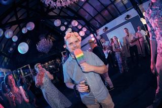 Bruidegom Krijn danst met regenboogvlag op trouwfeest Evelien en Krijn, De Schaapskooi Delft, trouwreportage - Trouwshoot Ste