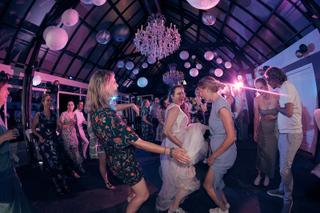Bruid Evelien danst met gasten op feestelijke trouwreceptie De Schaapskooi Delft, DJ-verlichting en kristallen kroonluchters,