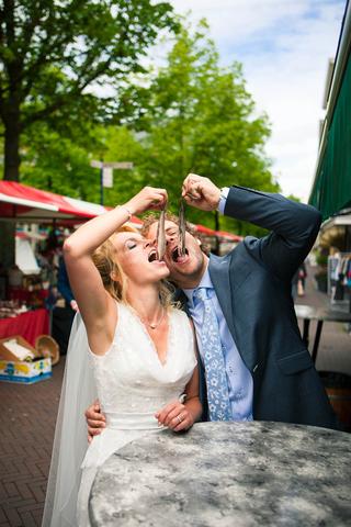 Bruidspaar Monique en Oude Jan eten haring op hun trouwdag bij Boerderij Dichtbij - Trouwshoot Stefan Segers