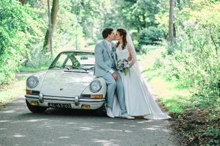 Bruidspaar Patrick en Lyn kussen bij vintage Porsche tussen groene bomen in Delftse Hout - Trouwshoot Stefan Segers