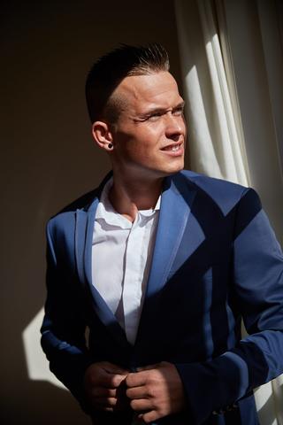 Bruidegom Jeffrey in donkerblauw pak bij raam, trouwreportage Voorburg Delft - Trouwshoot Stefan Segers