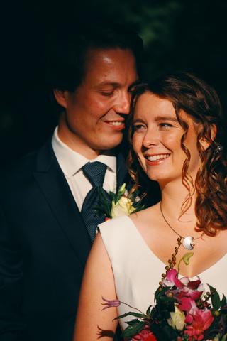 Gelukkig bruidspaar lacht samen met bruidsboeket, trouwreportage Delft stadhuis - Trouwshoot Stefan Segers