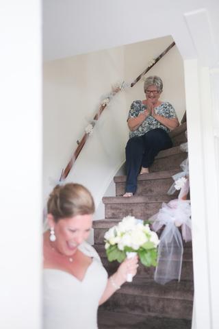 Bruid Deborah met wit bruidsboeket op trap, moeder kijkt emotioneel toe - Trouwshoot Stefan Segers