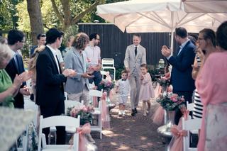 Bruidspaar Evelien en Krijn verlaat ceremonie met bruidskinderen onder applaus, tuinfeest De Schaapskooi Delft - Trouwshoot S