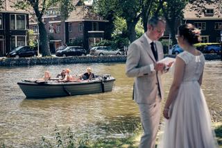 Bruidspaar Evelien en Krijn aan kanaal in Delft, gasten in bootjes, trouwreportage De Schaapskooi - Trouwshoot Stefan Segers