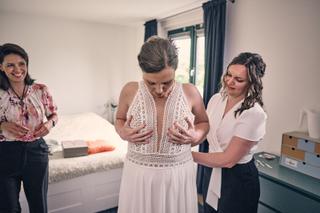 Bruid Huszár krijgt hulp bij aankleden in hotelkamer, vriendelijke trouwvoorbereiding Delft, bruidsfotografie - Trouwshoot St