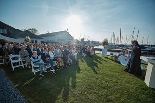 Bruidspaar Carlo en Lucinda ceremonie aan het water bij Kasteel Sypesteyn Loosdrecht, gasten op gazon met zeilboten op achter