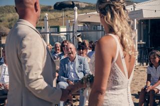 Bruidspaar Chris en Gerco trouwceremonie Strandclub Naturel Scheveningen, gasten lachen bij strandhuwelijk - Trouwshoot Stefa