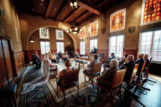 Bruid Helen en bruidegom Burt trouwen in Raadhuis Leidschendam, ceremonie met gasten in rustieke zaal met glas-in-lood ramen