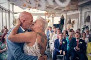 Bruidspaar Silvia en Patrick kust elkaar tijdens trouwceremonie Beachhouse Kijkduin Den Haag, gasten applaudisseren - Trouwsh