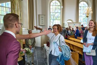 Tijdens de bruiloft van Emmely en Tom bij Villa Ockenburgh: een gelukkig moment in de kerk terwijl gasten toekijken en juiche