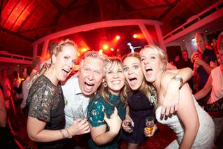 Bruidspaar Michael en gasten feesten uitgelaten op dancefloor met rood licht, trouwfeest Soda Fabriek - Trouwshoot Stefan Seg