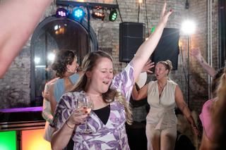 Bruidsgasten dansen uitgelaten op trouwfeest in Sodafabriek Schiedam, avondreportage met kleurige discolichting - Trouwshoot