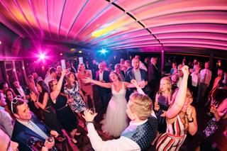 Bruid Victoria danst uitgelaten met gasten op feestelijk verlichte dansvloer - Trouwshoot Stefan Segers