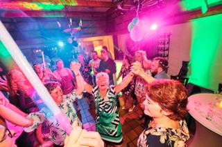 Bruidsgasten dansen feestelijk op trouwreceptie Patrick en Lyn in Ter Aar, neon verlichting en sfeer, trouwreportage - Trouws
