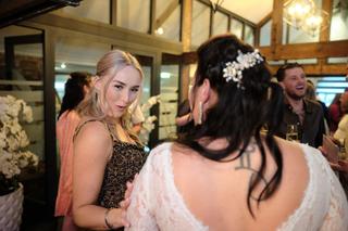 Bruid in witte kanten jurk met bloemen in haar haren danst met gast in elegant zwart gekleed, receptie Sodafabriek Schiedam,