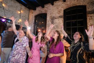 Bruidsgasten dansen vrolijk met handen omhoog op trouwfeest Sodafabriek Schiedam, avondreportage - Trouwshoot Stefan Segers