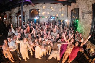 Vrolijk bruidspaar danst met gasten tijdens trouwfeest in Sodafabriek Schiedam, uitgelaten trouwreportage - Trouwshoot Stefan