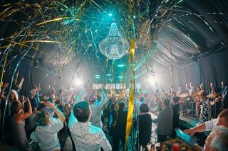 Bruidspaar Maud en Sander feest met gasten onder gouden confetti en kristallen kroonluchter, trouwreportage Fort 1881 - Trouw