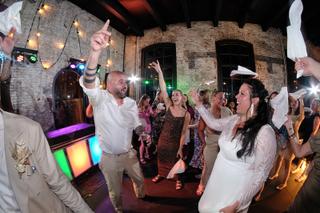 Bruidspaar danst uitbundig met gasten in Torpedoloods Schiedam, festive trouwreportage met neon verlichting - Trouwshoot Stef