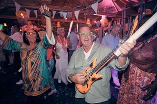 Bruidspaar Silvia en Patrick feest op trouwfeest Beachhouse Kijkduin Den Haag, gasten dansen met gitaar en feesthoedjes, fest