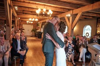 Bruidspaar Ilse en Robbert kust elkaar tijdens eerste dans in rustieke schuur Boerderij Burgersdijk De Lier, gasten applaudis