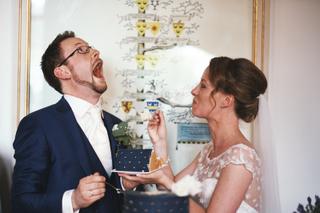 Bruidspaar eet bruidstaart op kasteel Duivenvoorde, groom kijkt omhoog in grappig moment - Trouwshoot Stefan Segers