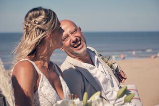 Bruidspaar Chris en Gerco lacht aan het strand Scheveningen, trouwceremonie strandclub, bruidsfotografie - Trouwshoot Stefan