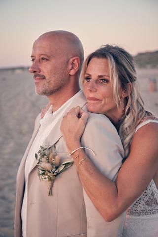 Bruidspaar Chris en Jolanda omhelst elkaar bij zonsondergang op het strand, trouwreportage Scheveningen - Trouwshoot Stefan S