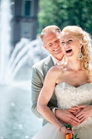 Bruidspaar Neomi en Michael lacht gelukkig bij fontein Hotel des Indes Den Haag, trouwreportage - Trouwshoot Stefan Segers