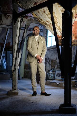 Bruidegom in beige pak staat in verlaten industrieel pand Sodafabriek Schiedam, trouwreportage - Trouwshoot Stefan Segers